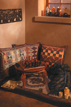 
A folding chess table with detachable legs, carved out of kepelan wood by Balinese artist Ketut Sandi, and a collection of pillows screen-printed from potato print designs by Zimbabwean artist Freeborn Sigauke (both from Novica.com) welcome aficionados and would-be chess players alike. A metal wall hanging of trumpeting angels made by Haitian artists from oil drums (tenthousandvillages.com) adorns the wall, while handblown glass balls from the Mexican village of Tonala (eZiba.com) catch sun in the window. A hand-felted wool rug from Turkmenistan and a handwoven ikat blanket from Thailand (both from womankind.com) complete this comfortable corner.
